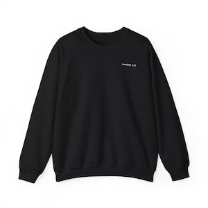 May include: Black crew neck sweatshirt with the text "running 1/1" in white, located on the upper chest. The sweatshirt has long sleeves and a simple, minimalist design, suitable for casual wear.