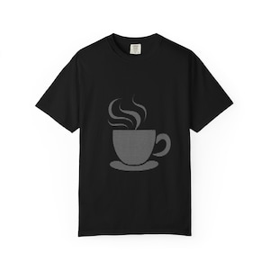 Puede incluir: Camiseta negra con un gráfico gris de una taza de café humeante sobre un platillo. La taza y el vapor están creados con líneas horizontales. La camiseta tiene mangas cortas y cuello redondo.