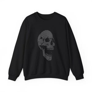 May include: Black sweatshirt with a grey, pixelated skull graphic on the front. The skull design is made up of horizontal lines, creating a digital effect. The crew neck sweatshirt has long sleeves and a classic fit, suitable for casual wear.