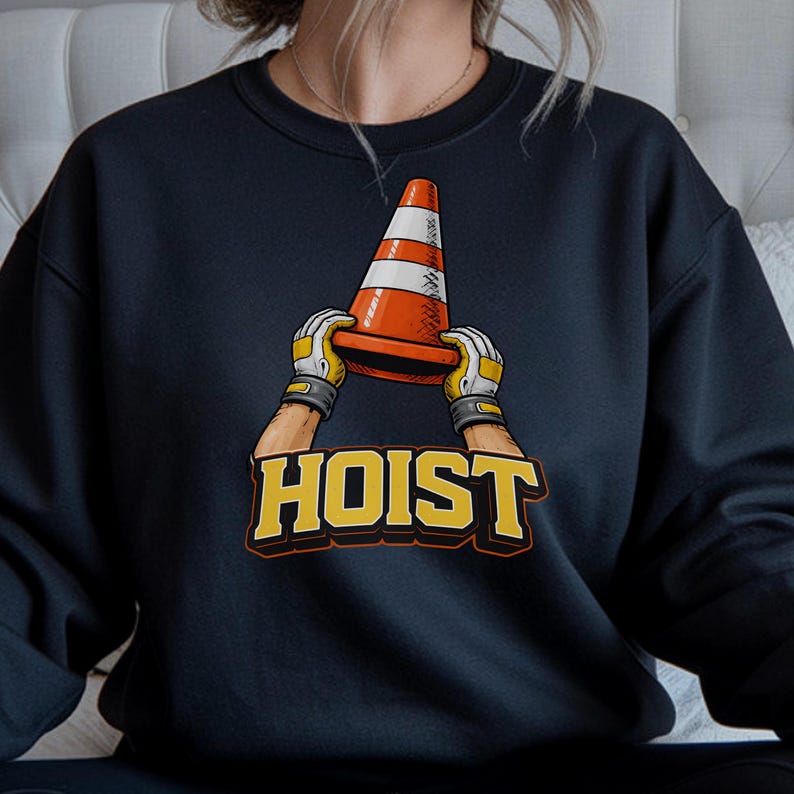 May include: Navy blue sweatshirt featuring a graphic of a traffic cone held by gloved hands. The word "HOIST" is printed in yellow and orange. The design is a playful take on construction themes.