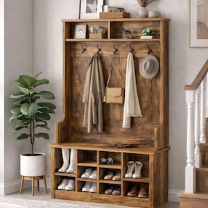 May include: Wooden entryway storage bench with a built-in shoe rack and coat rack. The bench has a distressed finish and features multiple cubbies for shoes, hooks for coats, and a top shelf for decor. A neutral rug and potted plant are in the foreground.