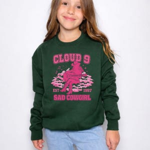 May include: A white ceramic mug with a black handle and the text "But First, Coffee" in a bold, black font. The mug is set against a blurred background, suggesting a cosy setting.