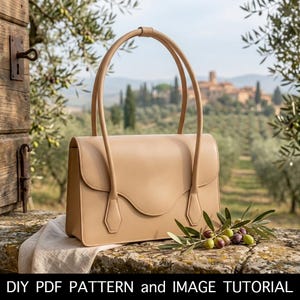 May include: A beige leather handbag with long handles, set against a scenic outdoor backdrop. The bag has a structured design with a curved flap and is placed on a stone surface. Olive branches with olives are in the foreground. Text at the bottom reads "DIY PDF PATTERN and IMAGE TUTORIAL".