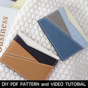 Puede incluir: Dos tarjeteros de cuero con diseños geométricos de bloques de color. Uno es marrón, negro y blanco, el otro azul, gris y crema. Ambos tienen costuras blancas y están sobre una superficie blanca texturizada. El texto en la parte inferior dice "DIY PDF PATTERN and VIDEO TUTORIAL."