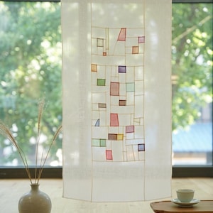 Puede incluir: Un panel de tela rectangular, de color blanco roto y semitransparente, que presenta una sección vertical central compuesta por una cuadrícula de líneas finas claras y pequeños parches geométricos multicolores dispersos en rojo, azul, verde y marrón.