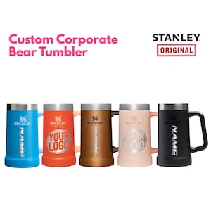 Könnte beinhalten: Fünf Stanley Bear Tumbler in verschiedenen Farben: Blau, Orange, Bronze, Rosa und Schwarz. Jeder Becher hat einen Griff und das Stanley-Logo. Der Text "Custom Corporate Bear Tumbler" ist über den Bechern zu sehen.