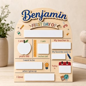 Peut inclure: Un panneau en bois clair en forme d'arche avec le prénom Benjamin écrit en bleu en haut. La planche présente le texte FIRST DAY OF et divers espaces blancs rectangulaires et en forme de pomme pour noter les détails de l'année scolaire.