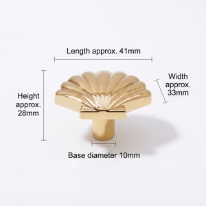 May include: A gold-colored cabinet knob shaped like a seashell. The knob features a ribbed fan design and a cylindrical base. Dimensions are labeled as length approx. 41mm, width approx. 33mm, height approx. 28mm, and a base diameter of 10mm.