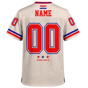 May include: A beige mesh jersey featuring the word NAME in red letters above the number 00 in red with blue outlines. The Croatian flag is centered at the top. The sleeves have red and blue stripes, and the text FOOTBALL LEGACY 26 appears below the number with three stars.