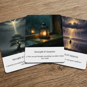 May include: Three rectangular cards with rounded corners featuring artistic illustrations. The center card displays a lit lantern on a ledge with the text Strength & Surprise and A time you got through something you didn't think you could.