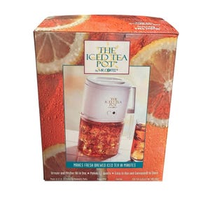 May include: The Iced Tea Pot by Mr. Coffee. The box features a white iced tea maker with a clear pitcher filled with iced tea. The box has a background of orange slices and text that reads "MAKES FRESH BREWED ICED TEA IN MINUTES."