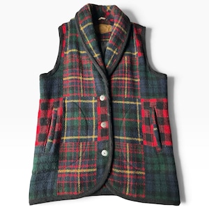 May include: A sleeveless vest featuring a multi-colored plaid pattern in shades of red, green, blue, and yellow. The garment has a shawl collar, three front buttons, and two side pockets. The edges are finished with black trim throughout.