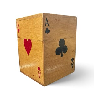 May include: A rectangular wooden box featuring a natural light brown wood grain finish. The exterior is decorated with red and black playing card suit symbols, including hearts and clubs, along with the letter A printed in the corners.