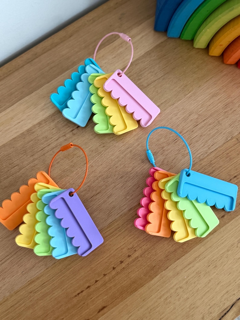 May include: Three sets of plastic scalloped tags in various colors, including pink, yellow, green, blue, orange, and purple. Each set is held together by a flexible metal cable ring, allowing the individual tags to fan out in a circular arrangement.