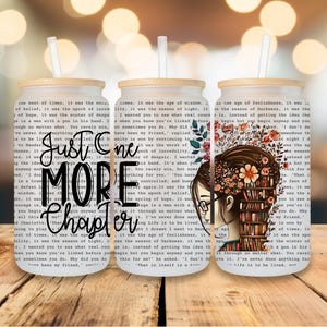 May include: Three glass tumblers with bamboo lids and straws. The tumblers feature a book-themed design with the text "Just One More Chapter." One tumbler has a floral design with a woman's silhouette. The background is a blurred bokeh effect.