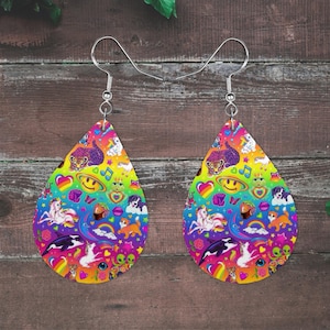 May include: A pair of teardrop-shaped earrings featuring a vibrant, multi-colored rainbow background patterned with various small illustrations including unicorns, cats, dogs, hearts, smiley faces, rainbows, and musical notes, attached to silver-toned hooks.