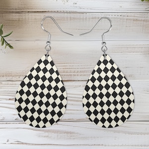 May include: A pair of teardrop-shaped dangle earrings featuring a black and white checkered diamond pattern. The earrings are suspended from silver-toned metal fishhook ear wires, creating a classic geometric design for everyday wear.