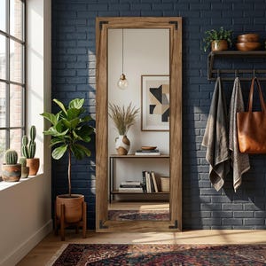 May include: A large, rectangular wooden framed mirror with dark metal corner accents. The mirror is positioned against a dark blue brick wall. The room features a rug, plants, and decorative items, creating a stylish interior design.