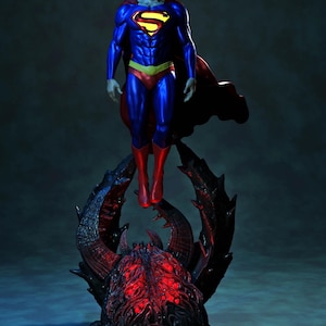 May include: A Superman figurine in a classic blue, red, and yellow costume, with a red cape, is posed mid-air above a dark, spiky base with red glowing accents. The figure has long, dark hair.