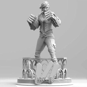 May include: A grayscale figurine of a character from the video game "Arcane: League of Legends." The figure is posed with clenched fists and wears a detailed outfit, including armored gauntlets. The base features the game's logo.