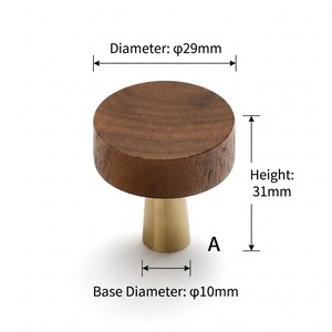 May include: A round wooden cabinet knob with a dark brown wood grain top and a brushed gold metal conical base. Technical labels indicate a diameter of 29mm, a height of 31mm, and a base diameter of 10mm. The letter A is printed near the base.