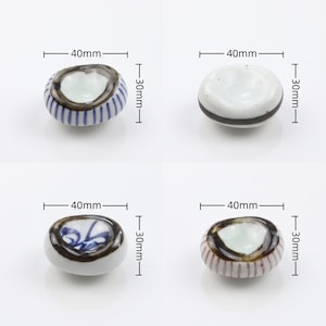 以下が含まれることがあります： 40mm x 30mmの陶磁器製箸置き4点。1つ目は青い縦縞、2つ目は黒い横帯、3つ目は青い花柄、4つ目は赤い縦縞に暗い縁取りが施されています。それぞれのサイズを示す寸法線が画像内に明記されています。