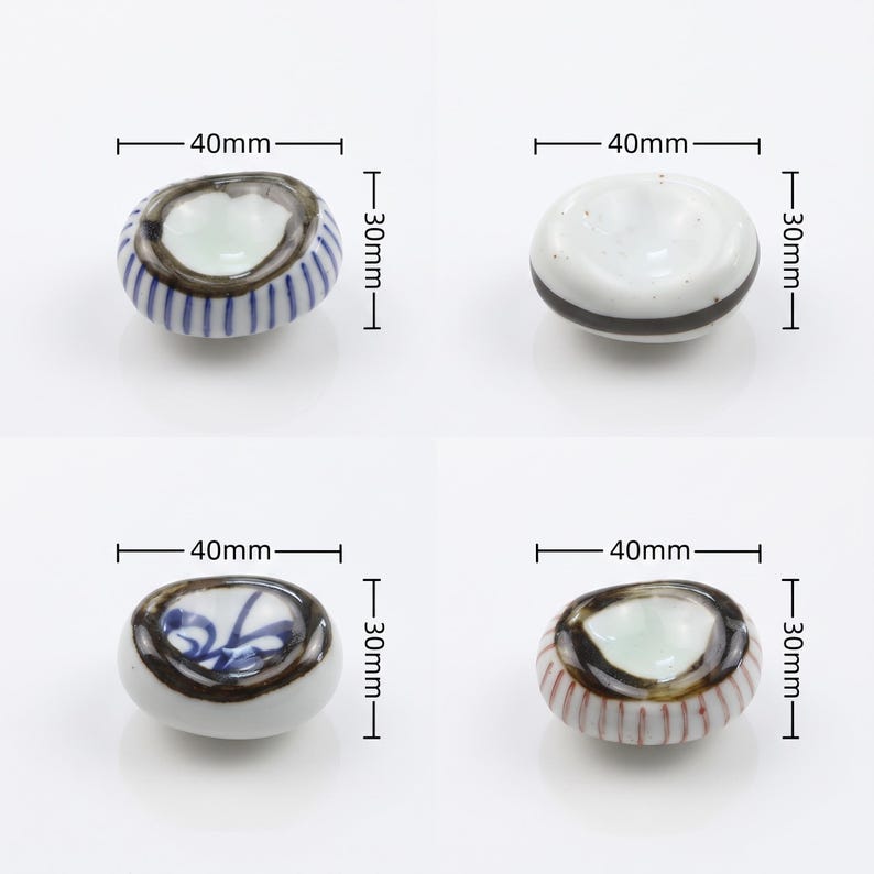 以下が含まれることがあります： 40mm x 30mmの陶磁器製箸置き4点。1つ目は青い縦縞、2つ目は黒い横帯、3つ目は青い花柄、4つ目は赤い縦縞に暗い縁取りが施されています。それぞれのサイズを示す寸法線が画像内に明記されています。