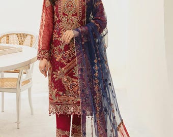 May include: A formal, embroidered burgundy ensemble featuring a long-sleeved tunic, matching pants, and a sheer navy blue scarf. The tunic has intricate gold and red embroidery. The outfit is suitable for special occasions.