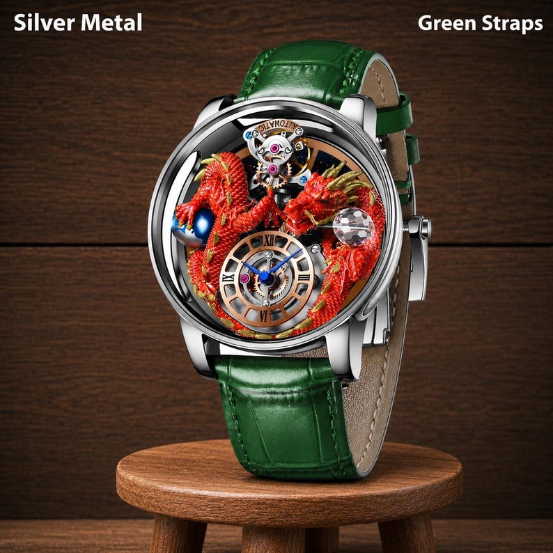 Op de afbeelding: Een zilvermetalen polshorloge met een groene leren band. De wijzerplaat heeft een gedetailleerd rood drakenontwerp en een zichtbaar mechanisch uurwerk. De wijzerplaat is rond met Romeinse cijfers.