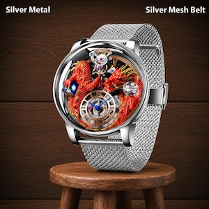 Op de afbeelding: Zilveren metalen polshorloge met een zilveren mesh band. De wijzerplaat van het horloge heeft een rood drakenontwerp met gouden accenten en zichtbare interne tandwielen. Het horloge wordt getoond op een kleine houten kruk.