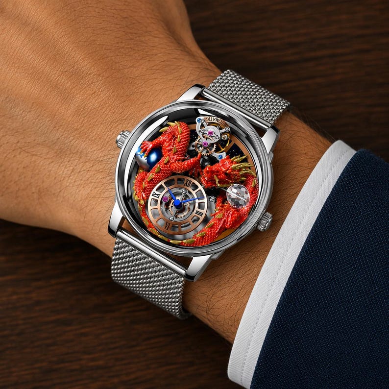 Op de afbeelding: Een zilveren polshorloge met een mesh band. De wijzerplaat van het horloge heeft een rood drakenontwerp met ingewikkelde details, een blauwe bol en een complex intern mechanisme. Het horloge zit om de pols van een persoon.