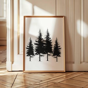 Könnte beinhalten: Ein gerahmter Kunstdruck mit einer minimalistischen Schwarz-Weiß-Illustration von vier immergrünen Bäumen. Das Kunstwerk wird in einem goldfarbenen Rahmen präsentiert und lehnt an einer weißen Wand und einem Holzboden.