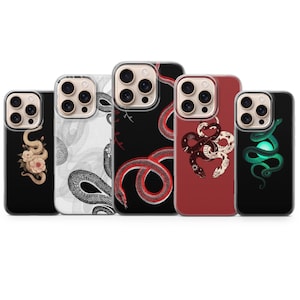 Op de afbeelding: Vijf smartphonehoesjes op een rij, elk met een unieke slangafbeelding. De ontwerpen omvatten een slang met roze bloemen op zwart, een wit slangenpatroon, een rode slang op zwart, twee verstrengelde slangen op rood en een lichtgevende groene slang.