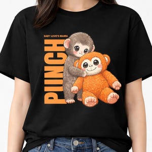 May include: Black t-shirt featuring a cartoon illustration of two monkeys hugging. The text "PUNCH" is printed vertically in orange, with "BABY LOVE'S MAMA" above it. The monkeys are brown and orange.