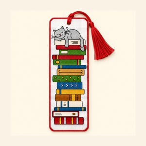 Op de afbeelding: Een rechthoekige kruissteek boekenlegger met een stapel kleurrijke boeken en een slapende grijze kat erbovenop. De boekenlegger heeft een witte rasterachtergrond, een rode rand en een rode kwast die met een lus aan de bovenkant vastzit.
