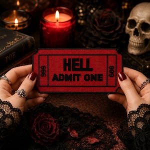 May include: A rectangular red and black embroidered patch shaped like a ticket. The text HELL ADMIT ONE is centered in black lettering. The number 666 is visible on both the left and right sides of the ticket design, enclosed within black borders.