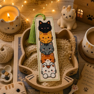 Adorable cat stack cross stitch bookmark pattern featuring five kawaii cats peeking one above another in black, orange, gray, orange-and-white, and white colors. This cute animal bookmark design is stitched with 9 DMC colors and measures 40 × 125 stitches. Perfect for cat lovers, bookworms, and beginner to intermediate cross stitch enthusiasts. Ideal as a handmade reading accessory, thoughtful gift, or DIY embroidery project with instant PDF download for creating a charming bookmark.