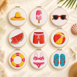 Peut inclure: Neuf tambours à broder circulaires en bois présentant des motifs au point de croix sur le thème de l'été : un chapeau de soleil jaune, une glace rose, des lunettes rouges, des tranches de pastèque, un short de bain rouge, un ballon de plage, une bouée, un bikini rose et des tongs bleues.