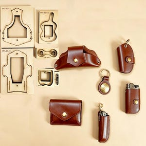 May include: A selection of brown leather accessories, such as a wallet, keyrings, lighter cases, and a belt pouch. Also shown are wooden die-cut templates for leather crafting. The items are arranged on a neutral background.