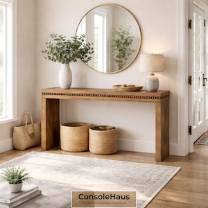 May include: A wooden console table with a decorative beaded edge, topped with a white vase holding greenery, a lamp, and a round mirror. Two woven baskets sit below. The text "ConsoleHaus Modern Entryway Furniture" is at the bottom.