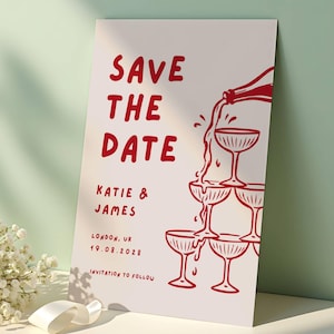 Può includere: Un biglietto bianco "Save the Date" con testo e illustrazioni rosse. Il biglietto presenta il testo "SAVE THE DATE", i nomi "KATIE & JAMES" e la data "19.08.2028". È incluso anche un disegno di champagne versato in una torre di bicchieri.
