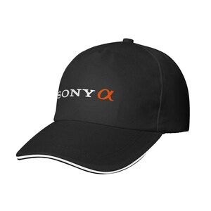 May include: Black baseball cap with a curved brim and white trim. The cap features the white text "SONY" and the orange "α" logo on the front. The cap is a classic style, suitable for outdoor activities.