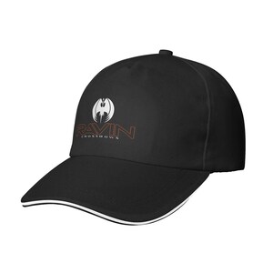 May include: Black baseball cap with a curved brim and a white trim. The cap features the word "RAVIN" in orange and white, with a stylized logo above the text. The words "CROSSDOWNS" are below the word RAVIN.