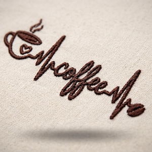 May include: A dark brown embroidery design on a light beige fabric background. The design features a coffee cup with a small heart, transitioning into a heartbeat line that forms the word coffee, ending with a single coffee bean icon.