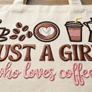 May include: Cream-colored tote bag with embroidered coffee-themed designs. Features a coffee cup, coffee beans, a heart-shaped design, a to-go cup, and a coffee pot. Text reads "JUST A GIRL who loves coffee" in brown and pink thread.