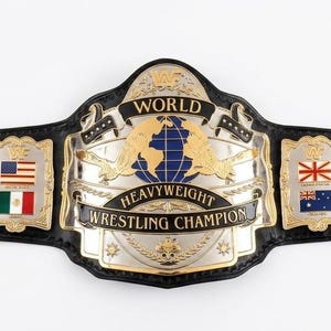 Könnte beinhalten: Ein schwarzer Wrestling-Meisterschaftsgürtel aus Leder mit einer großen zentralen Gold- und Silberplatte mit der Aufschrift WORLD HEAVYWEIGHT WRESTLING CHAMPION. Der Gürtel enthält Seitenplatten mit verschiedenen Nationalflaggen und goldene Metallnieten.