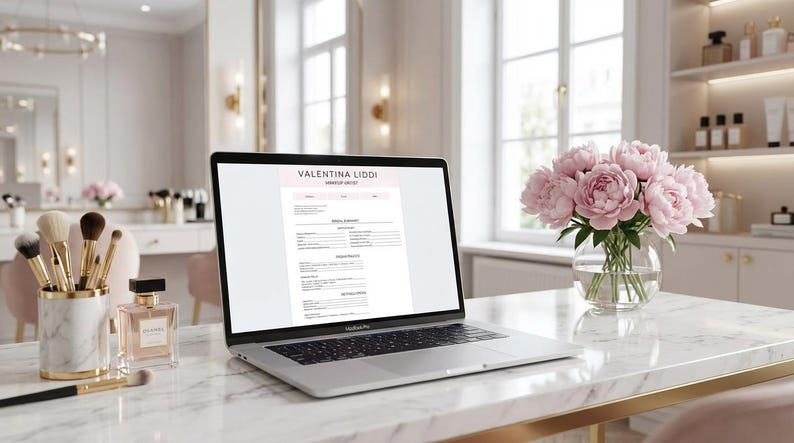 May include: A laptop displaying a document with the name "Valentina Liddi" sits on a marble desk. Makeup brushes, perfume, and a vase of pink peonies are also on the desk. The background features a vanity and a window.
