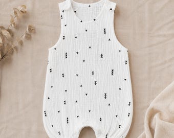 Könnte beinhalten: Weißer Baby-Strampler mit schwarzem Dreieckmuster. Der ärmellose Strampler hat einen runden Ausschnitt und Druckknöpfe am unteren Ende. Aus strukturiertem Stoff gefertigt, ist er auf Komfort und Bewegungsfreiheit ausgelegt.