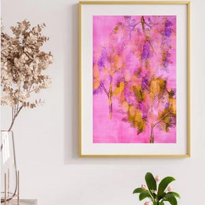 May include: A framed art print featuring a pink background with stylized tree branches in shades of yellow, purple, and green. The artwork is encased in a gold frame, creating a decorative piece for home decor.