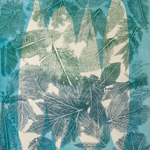 May include: A cyanotype print featuring a repeating pattern of various botanical leaf imprints in shades of dark teal and green. The composition includes a prominent white negative space shaped like a large letter M, layered over the foliage.